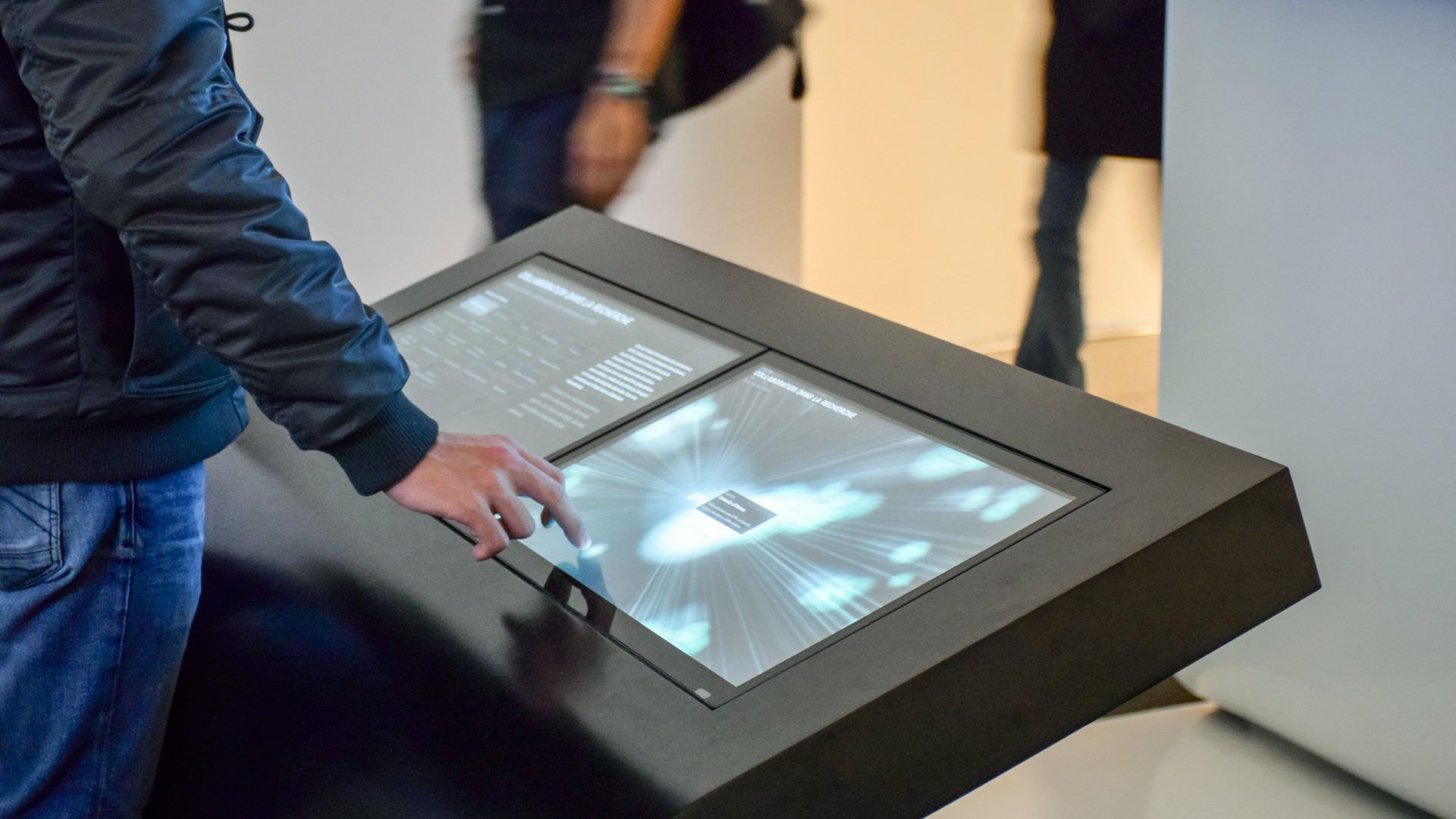 Visitor touching the monolith panel to explore the research collaborations visualization at the exhibition