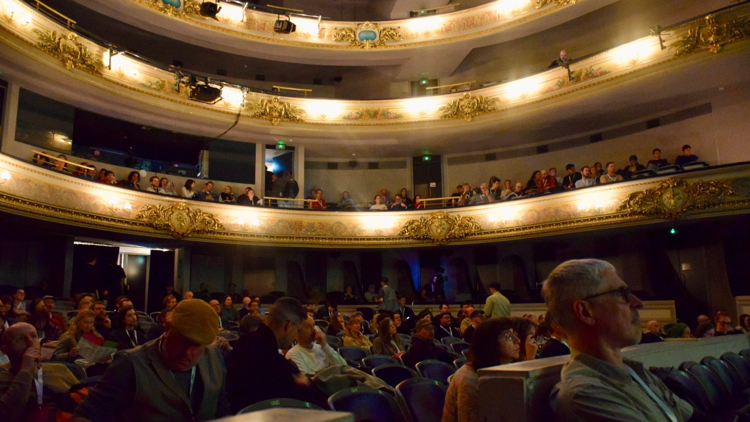 Audience in the stalls and gilded balconies of the Théâtre de Namur before the talk