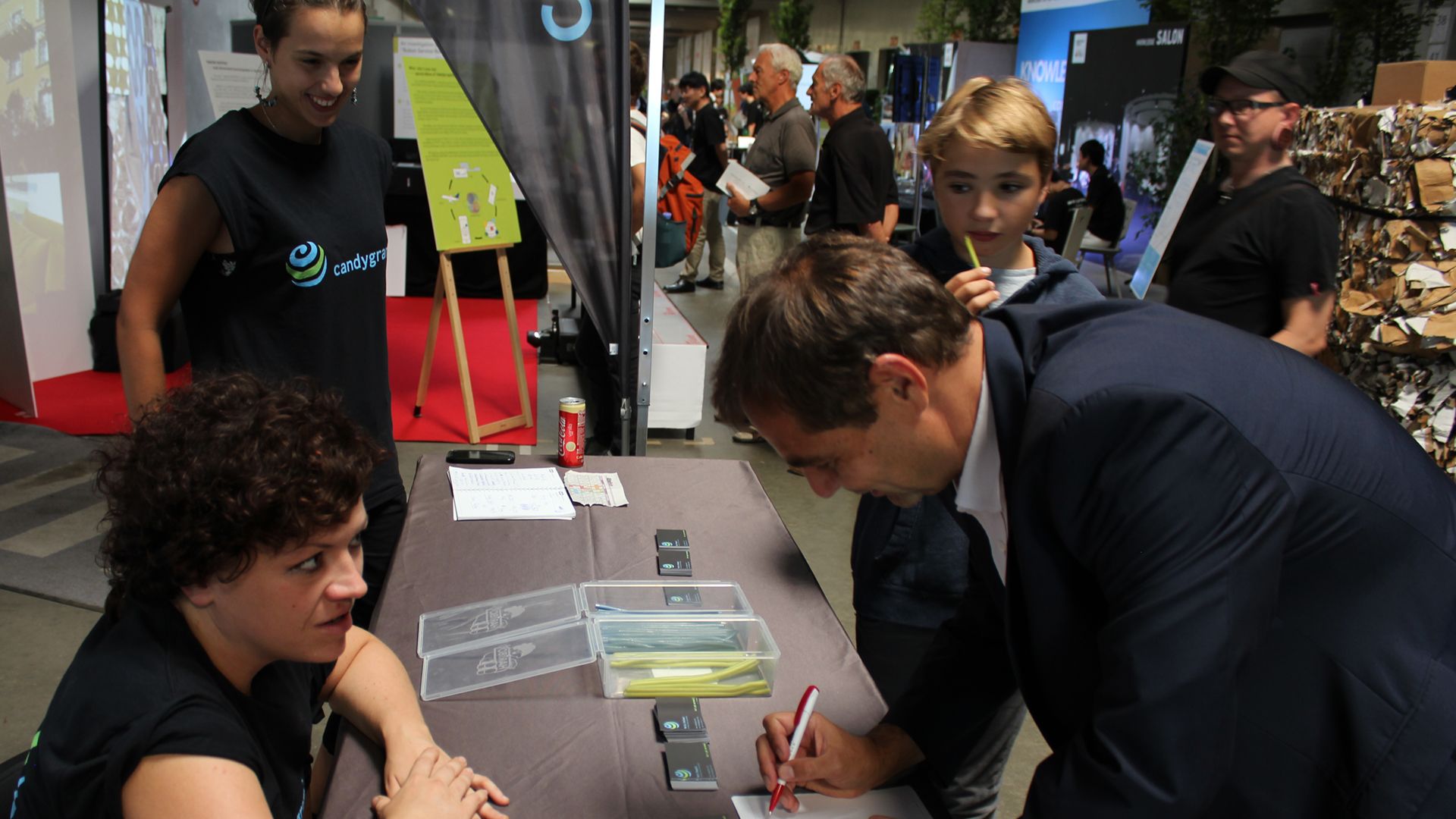 Visitor signing up at the Candygram booth while a staffer in a branded shirt looks on