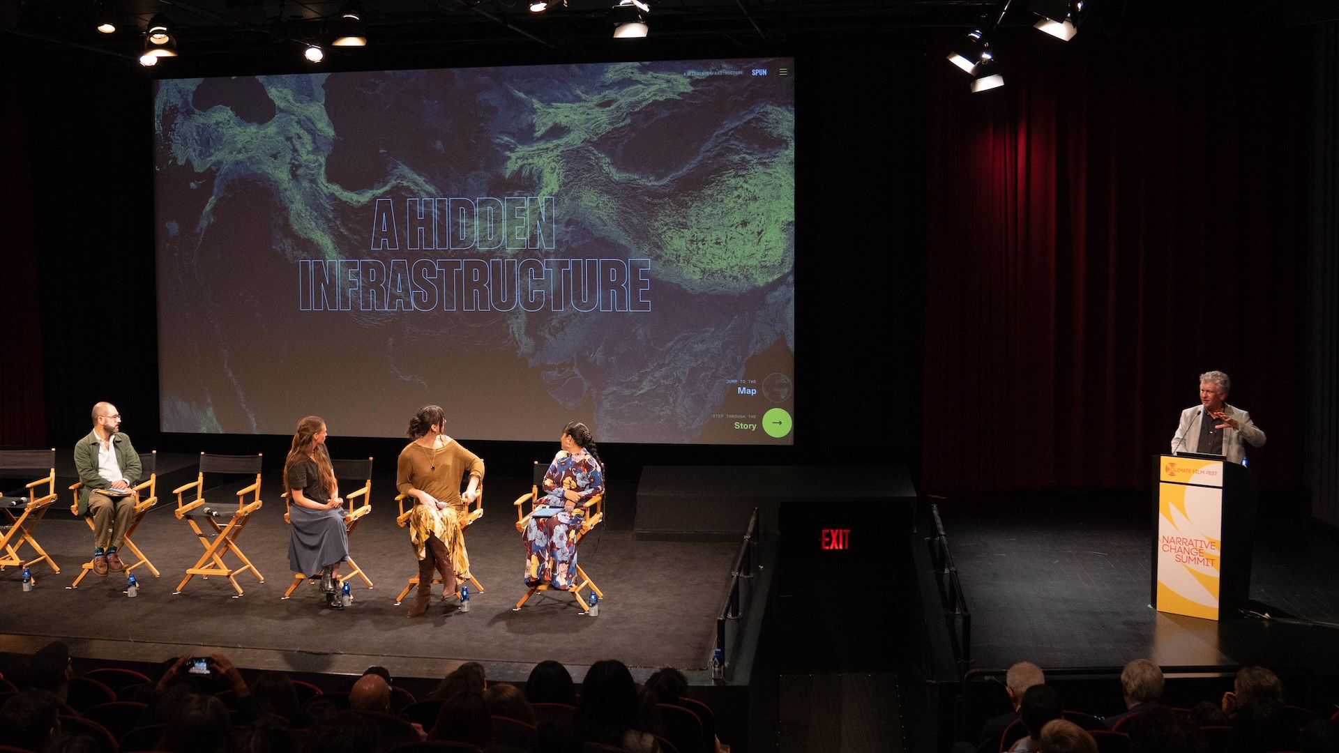 Projected title screen of "A Hidden Infrastructure", a blue and green map of underground fungal networks, with Moritz Stefaner at the podium and panelists seated on stage