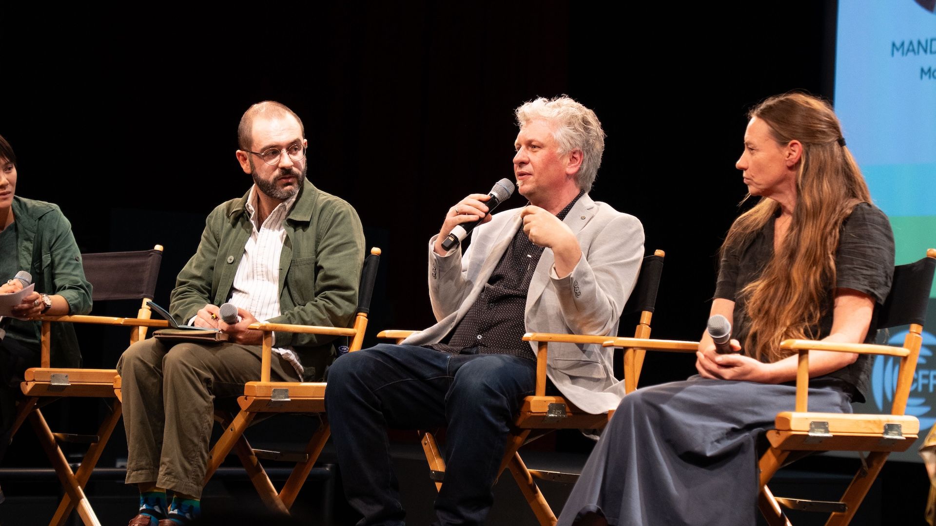 Moritz Stefaner speaking into a handheld microphone, seated between two fellow panelists