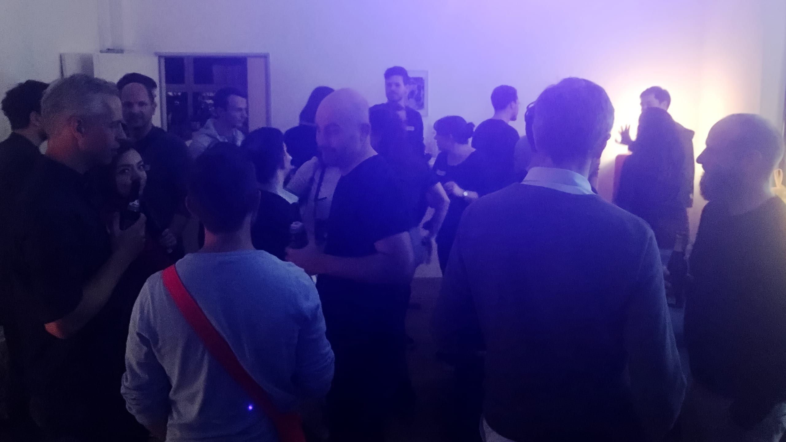 Listeners mingling in dim, colourful light at a Data Stories meetup