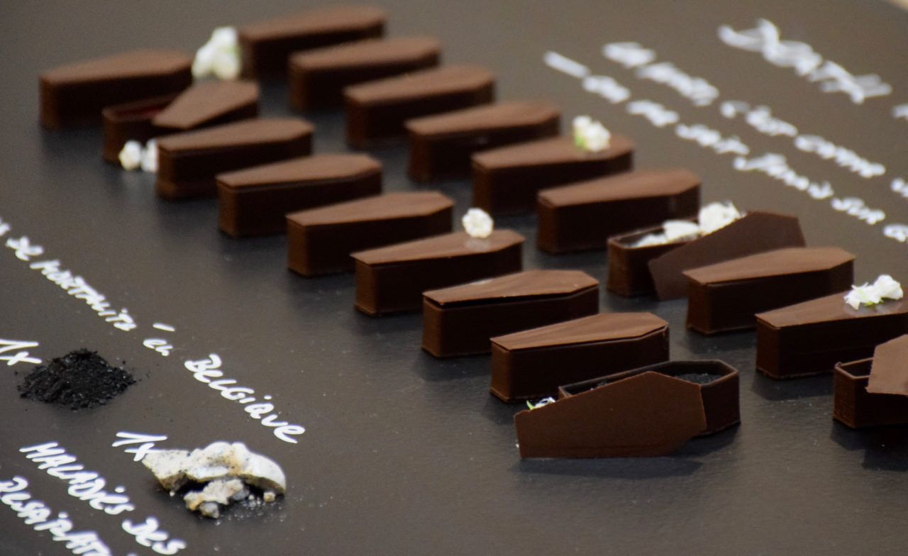 Data Cuisine praline coffins in rows on a dark board with handwritten mortality labels