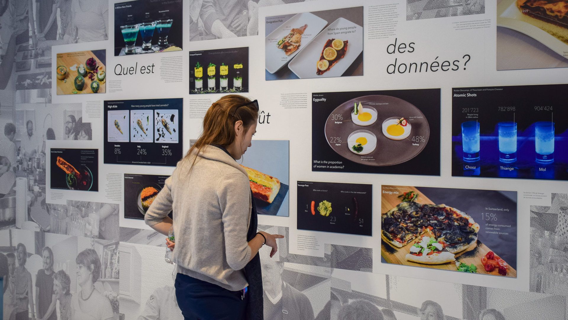 Visitor at the Data Cuisine wall of edible data visualizations like Atomic Shots and Egguality