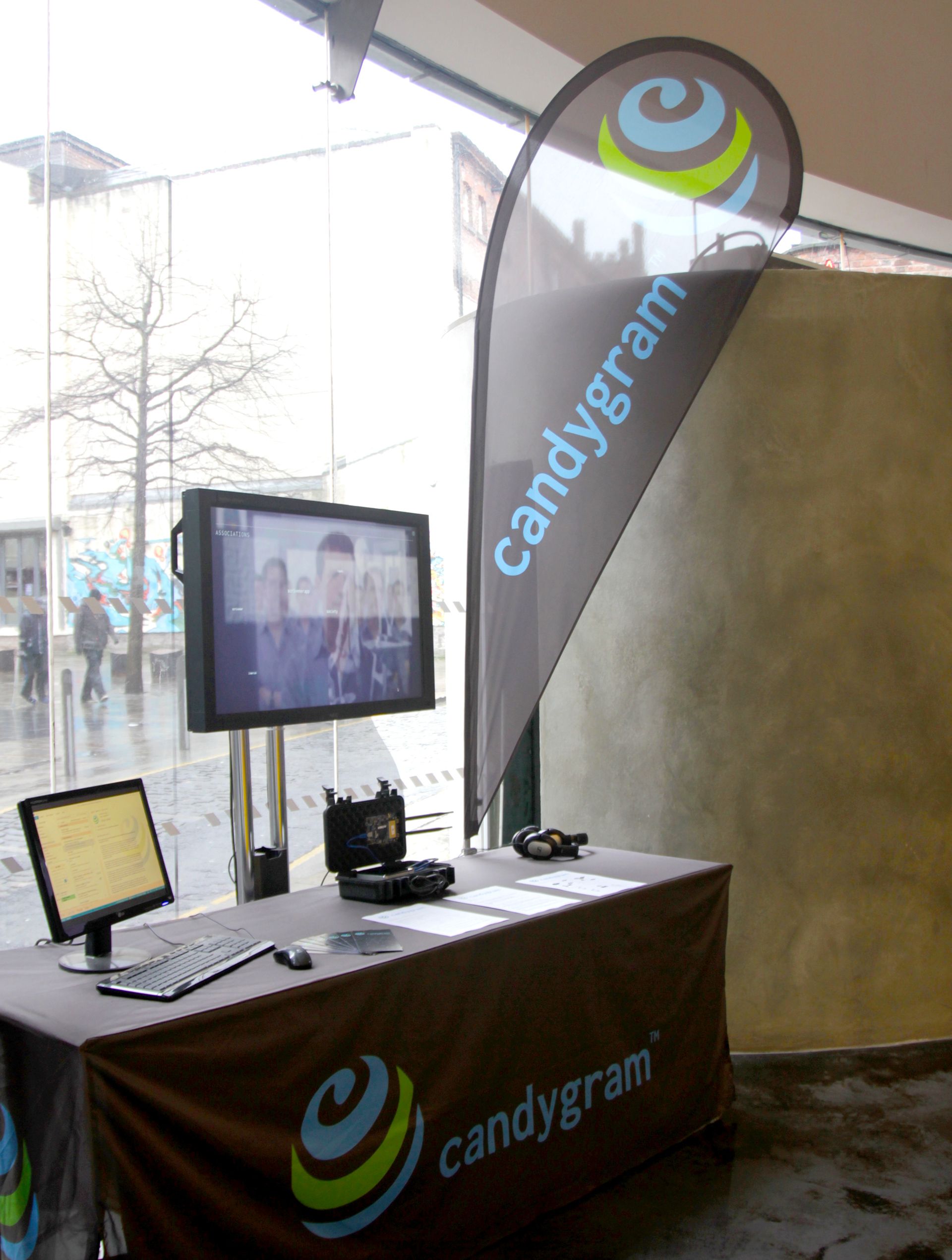Candygram booth with branded teardrop flag, a face-association screen, laptop and headphones